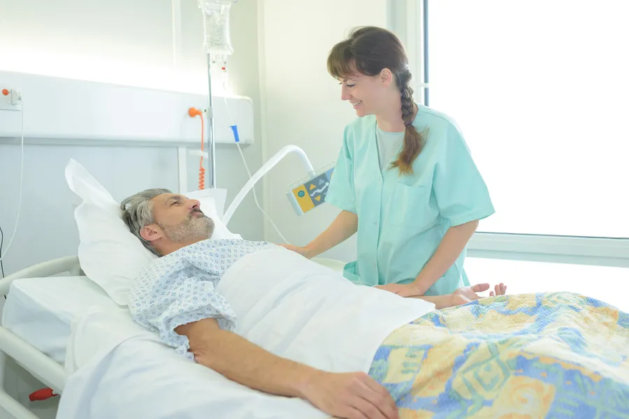 Pasient i seng og sykepleier