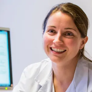 En person som smiler ved siden av en datamaskin