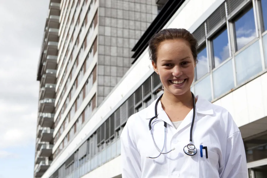 Bildet viser en legestudent i utdanning foran et sykehus.